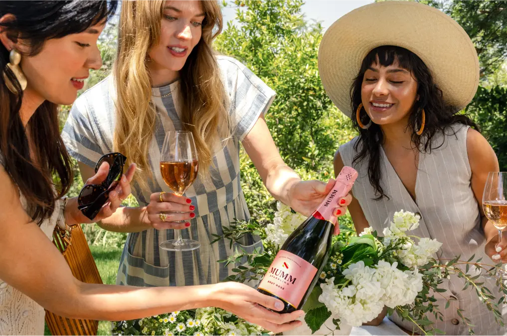 Friends checking out a bottle of Mumm Sparkling Brut Rosé